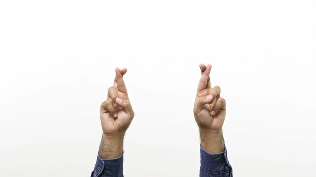 Close up of Man&rsquo;s hands keeping fingers crossed, waiting for special moment, making wish isolated over white background in studio.