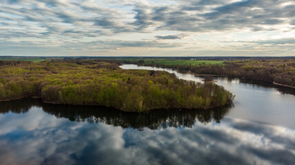 The view from the drone to the lake, reflected clouds in the water at sunset.