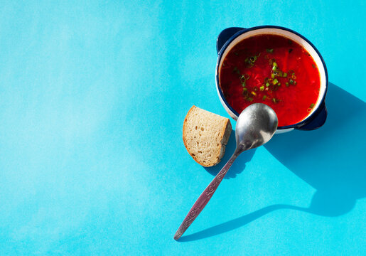  A plate with borscht, a metal tablespoon and a piece of rye bread. Red beet soup. National cuisine. Template for announcement flyers menu and entries.