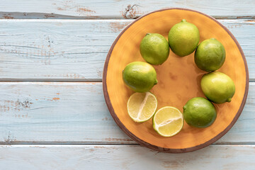 Lime fruits on yellow plate over blue wooden table.