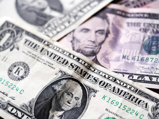 A photo illustration of US various dollar bills ibackground. Selective focus. 1 dollar bill at fioregraund