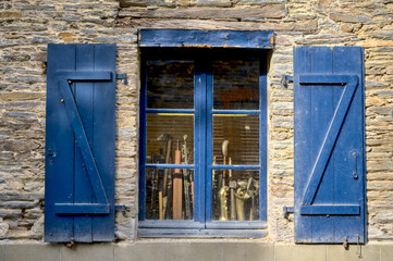 Antique traditional blue window in the village of La Gacilly in Brittany, France. We can see music instruments inside. 