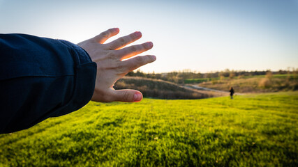 The man covers the shining sun straight to his face with his hand.