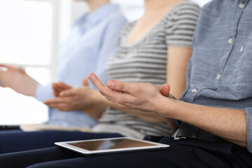 Business people clapping at meeting or conference, close-up of hands. Group of unknown businessmen and women in modern white office. Success teamwork, corporate coaching and applause concept