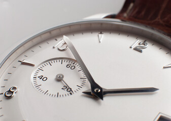 Detalle del segundero de un reloj de pulsera con la esfera de color blanco y las manecillas plateadas (macro)