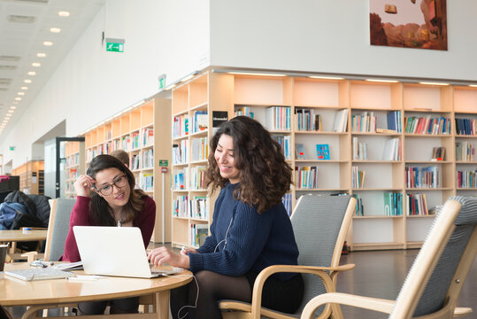 Female friends using laptop in library