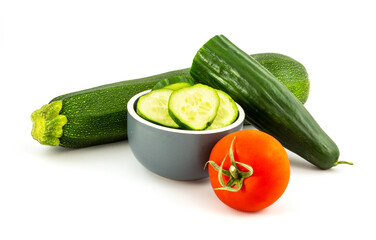 Sliced green cucumber, red tomato and green zucchine isolated on a white background.