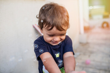 child with blue t-shirt playing with soap bubbles