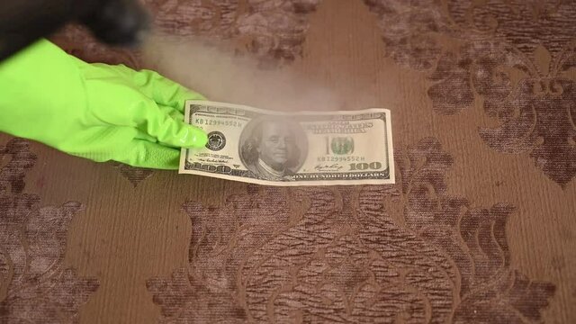 Disinfection of money. Gloved hands steam away germs. fight against coronavirus, covid-19. A dirty money source of infection. Misophobia, misophobia