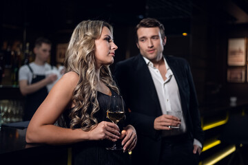charming girl and handsome man with cocktail glasses in a nightclub.