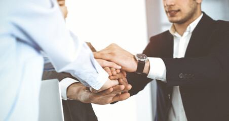 Fototapeta premium Business people group showing teamwork, joining hands and giving five to each other in sunny office