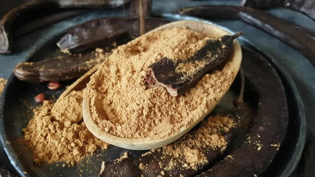 Dry carob pods and powder close up