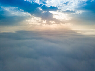 Fototapeta na wymiar Aerial drone flight over the fog. There are thick clouds of fog below, the sun breaks through the clouds.