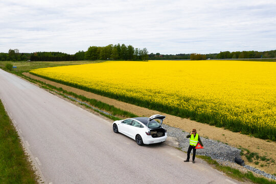 Man on side of road with broken down car