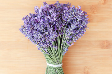 Fototapeta premium A bouquet of lavender on a wooden background. Fresh flower. Dark lilac and blue flowers of lavender.