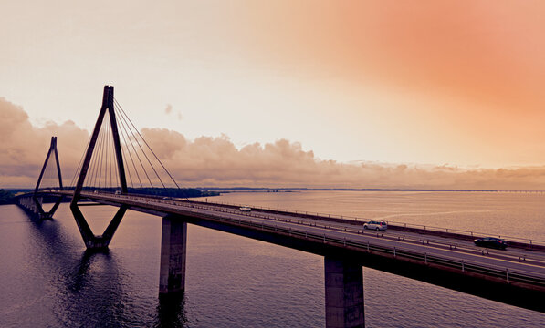 Large highway bridge with traffic passing over a bay at sunset.