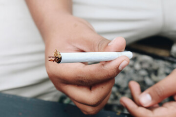 Man hand makes a cigarette with rolling traditional tools, hands closeup.