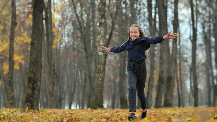 Fototapeta na wymiar Happy teenage girl runs in the autumn park.