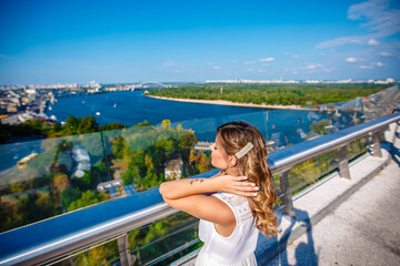 A young girl looks at the panorama of the city from the bridge. looks at the Dnieper river. Kiev