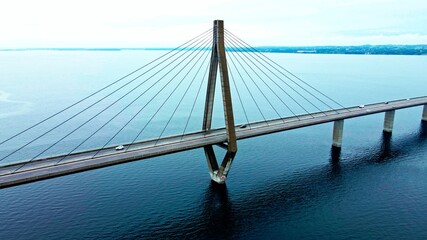 Large highway bridge spanning over a bay, with cars and trucks driving. Aerial view.