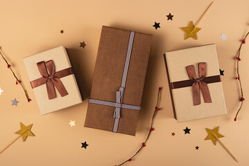 Brown boxes with ribbons - Christmas gifts on a neutral background with stars and twigs. Top view, flat lay