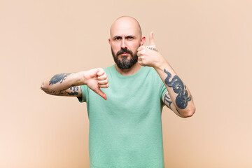 young bald and bearded man feeling confused, clueless and unsure, weighting the good and bad in...