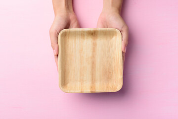 Betel palm leaf plate (Biodegradable plate, Compostable plate or Eco friendly disposable plate) holding by hand on pink background