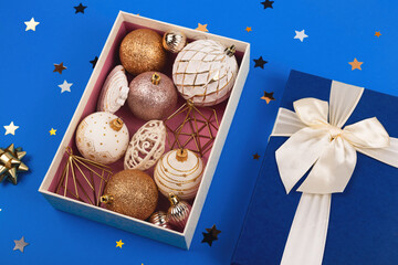 Minimalistic round white and gold Christmas balls in a blue box with a bow