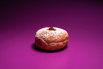 Sufganiya for Jewish holiday Hanukkah on violet background.