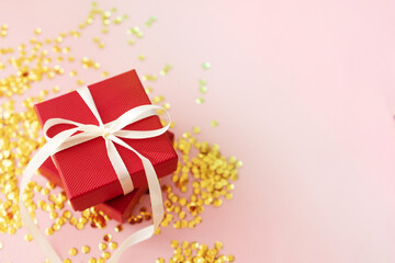
red gift box with bow on pink glitter background