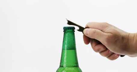 Mans hand opens a green beer bottle on white background