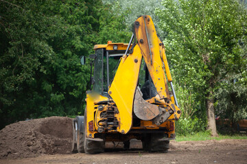 The excavator carries sand. Construction machinery on the street. Cleaning of sand with a bucket.