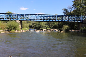 Beautiful old French railway bridge above a river. Photo was taken on a sunny day with an awesome blue sky.