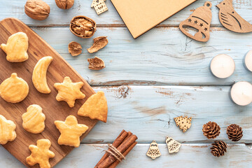 Christmas background with homemade Christmas cookies, walnuts, cinnamon sticks, pinecones, candles, wooden toys.