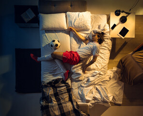 Comfort. Top view of young professional football, soccer player sleeping at his bedroom in...
