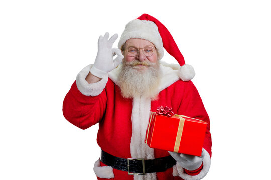 Portrait of Santa Claus with ok gesture. Happy Santa Claus with red gift box showing ok sign isolated on white background.