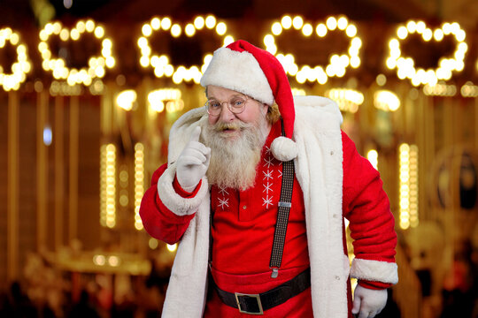 Santa Claus gesturing with index finger. Senior Santa Claus wagging his finger on blurred background. Keep the silence gesture.