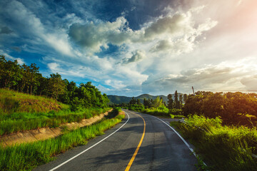 Empty asphalt road through the green field and clouds on blue sky in summer day. 