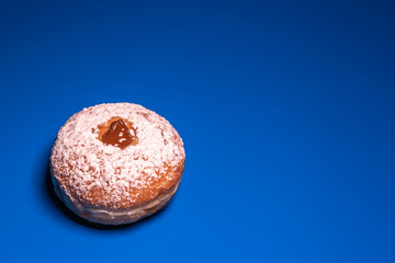 Sufganiya for Jewish holiday Hanukkah on blue background with copy space.