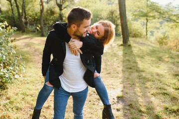 Fototapeta premium love, relationship, family and people concept - smiling couple having fun in autumn park