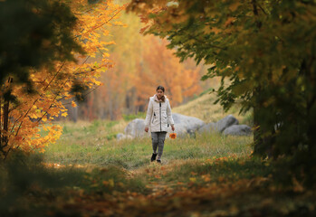 a young girl walks in the autumn maple alley