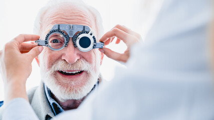 Smiling elderly man checking up vision with special ophthalmic glasses
