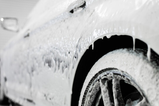 Car washing process. Foaming detergent covers side of the car, clean it from dirt and dust.