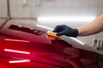 Man worker of car detailing studio applying ceramic coating on car paint with sponge applicator - 383882149