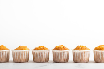 Fresh yellow muffins closeup on the white background