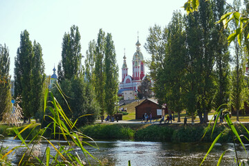 Fototapeta premium View of the Tamblva embankment and the bell tower of the Kazan monastery Tambov from the bank of the Tsna river on a summer day