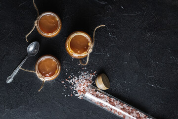 Homemade salted caramel sauce in jars and caramel candies