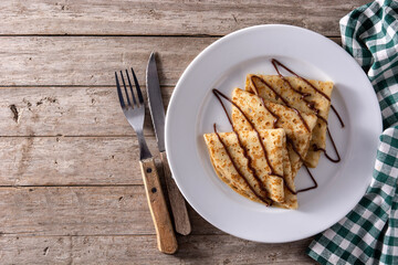 Sweet crepes with chocolate on wooden table. Top view. Copy space
