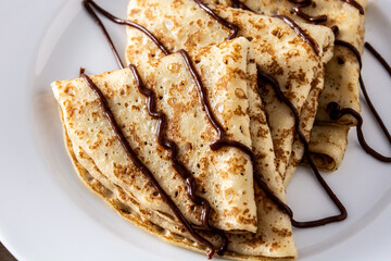 Sweet crepes with chocolate on wooden table