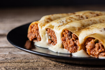 Delicious meat cannelloni pasta on rustic wooden table	